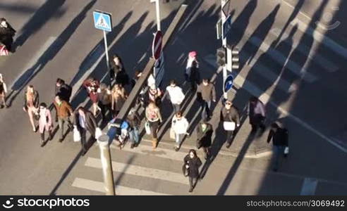 High angle shot shot of pedestrians starting walking across the road on zebra on green traffic light