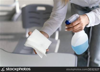 high angle teacher disinfecting school benches classroom