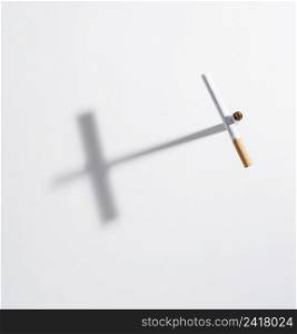 high angle view cross sign made from cigarette with it shadow isolated white background
