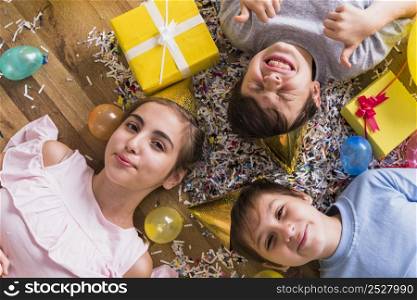 high angle view friends lying wooden floor surrounding by gift balloon confetti