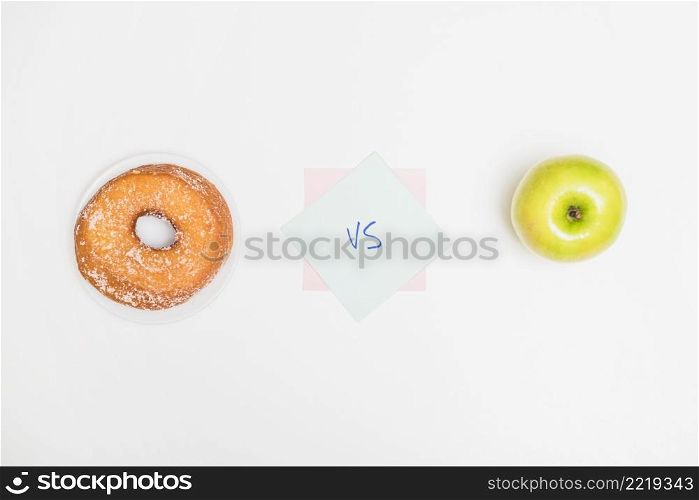 high angle view green apple versus donut white backdrop