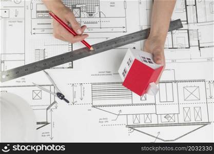 high angle view hand holding small house model pencil blueprint