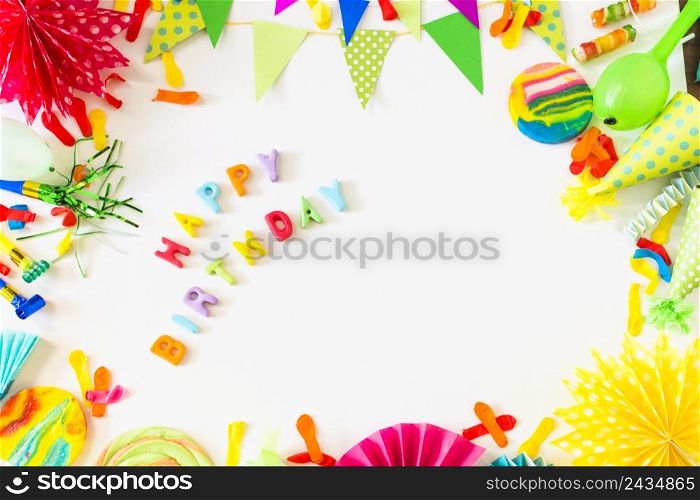 high angle view happy birthday text with party accessories white backdrop