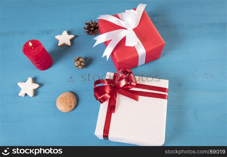 High angle view image with gift boxes, gingerbread cookies and a lit candle on a blue wooden table