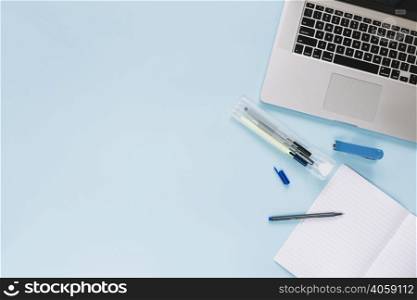 high angle view laptop stationeries blue background