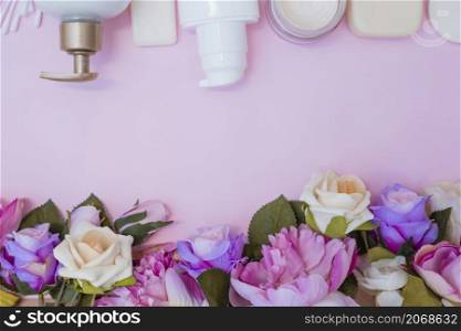 high angle view moisturizing cream fake flowers pink background