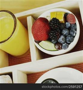 High angle view of a bowl of fruit and a glass of orange juice