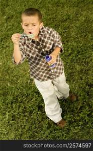 High angle view of a boy blowing bubbles with a bubble wand
