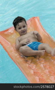 High angle view of a boy floating on a pool raft