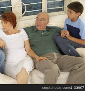 High angle view of a boy sitting on a couch with his grandparents