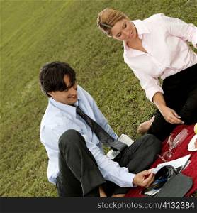 High angle view of a businessman and a businesswoman sitting together in the park