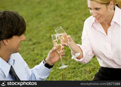 High angle view of a businessman and a businesswoman toasting with champagne flutes