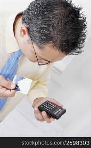 High angle view of a businessman holding a calculator and a credit card