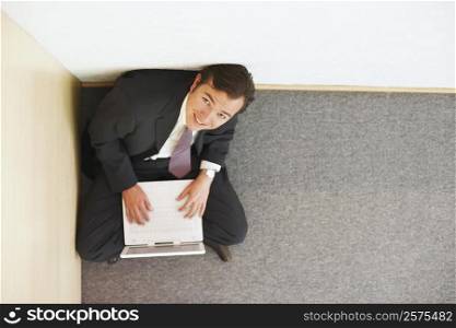 High angle view of a businessman sitting on the floor and using a laptop
