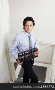 High angle view of a businessman standing on a staircase and holding an abacus
