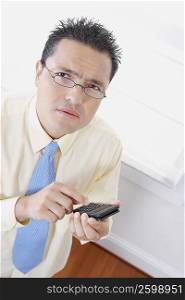 High angle view of a businessman using a calculator and thinking