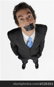 High angle view of a businessman with duct tape on his mouth