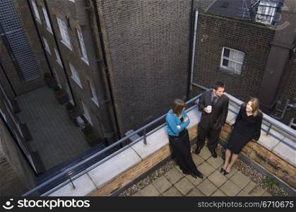 High angle view of a businessman with two businesswomen standing on the roof of a building
