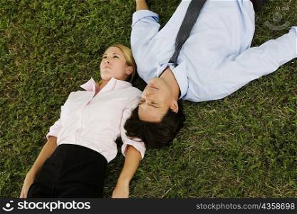 High angle view of a businesswoman and a businessman lying on the grass
