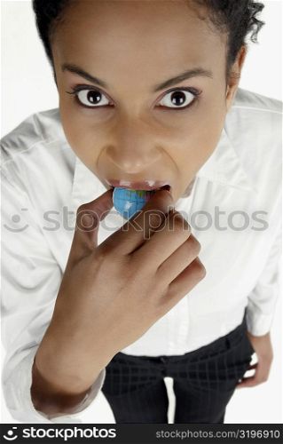 High angle view of a businesswoman holding a globe in her mouth
