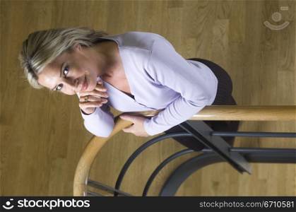 High angle view of a businesswoman leaning against a hand rail and smiling