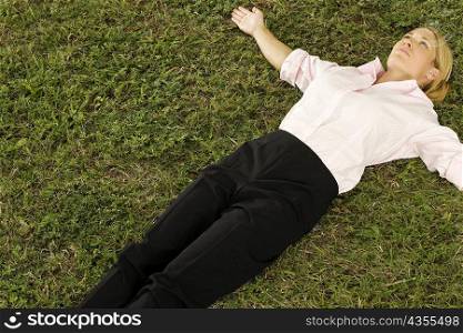 High angle view of a businesswoman lying on the grass