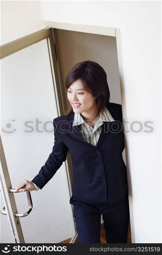 High angle view of a businesswoman opening a door and looking cheerful