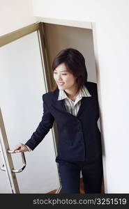 High angle view of a businesswoman opening a door and looking cheerful