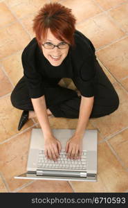 High angle view of a businesswoman sitting on the floor and working on a laptop