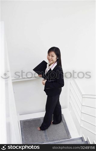 High angle view of a businesswoman standing on the staircase and smiling