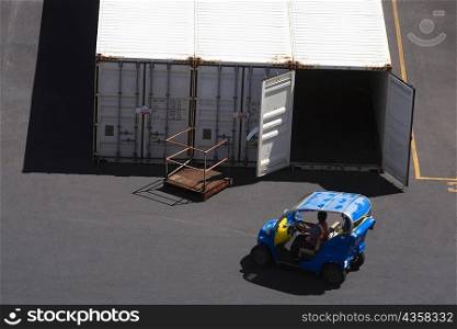 High angle view of a car in front of cargo containers at a commercial dock