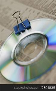 High angle view of a CD with a binder clip on a stock market data sheet