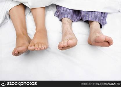 High angle view of a couple&acute;s feet on the bed