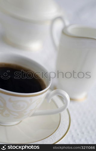 High angle view of a cup of black tea with a jug and a tea kettle