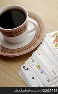 High angle view of a cup of black tea with playing cards