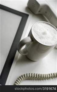 High angle view of a cup of coffee with a telephone receiver