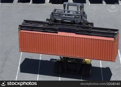 High angle view of a forklift picking up a cargo container at a commercial dock