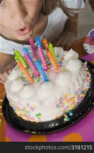 High angle view of a girl blowing candles on her birthday cake
