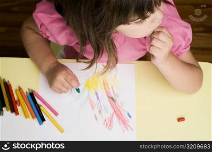 High angle view of a girl drawing on a sheet of paper and thinking