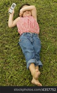 High angle view of a girl lying on the grass holding a mobile phone