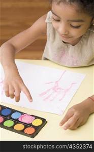 High angle view of a girl making handprint on a sheet of paper