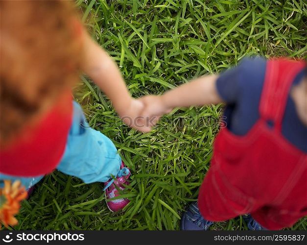 High angle view of a girl standing with a boy and holding hands