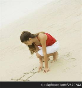 High angle view of a girl writing in sand