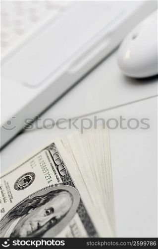 High angle view of a laptop with one hundred dollar bills