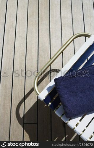 High angle view of a lounge chair and a towel on a floorboard