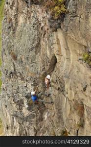 High angle view of a male and a female rock climber scaling a rock face