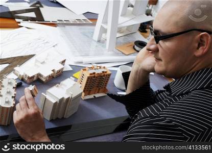 High angle view of a male architect looking at a building&acute;s model