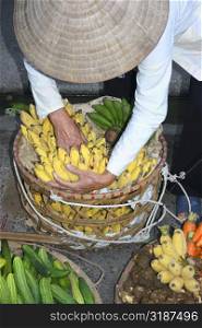 High angle view of a man arranging bananas in a basket, Hanoi, Vietnam