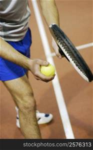 High angle view of a man holding a tennis ball and a tennis racket