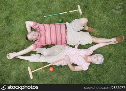High angle view of a mature couple lying on grass in a lawn